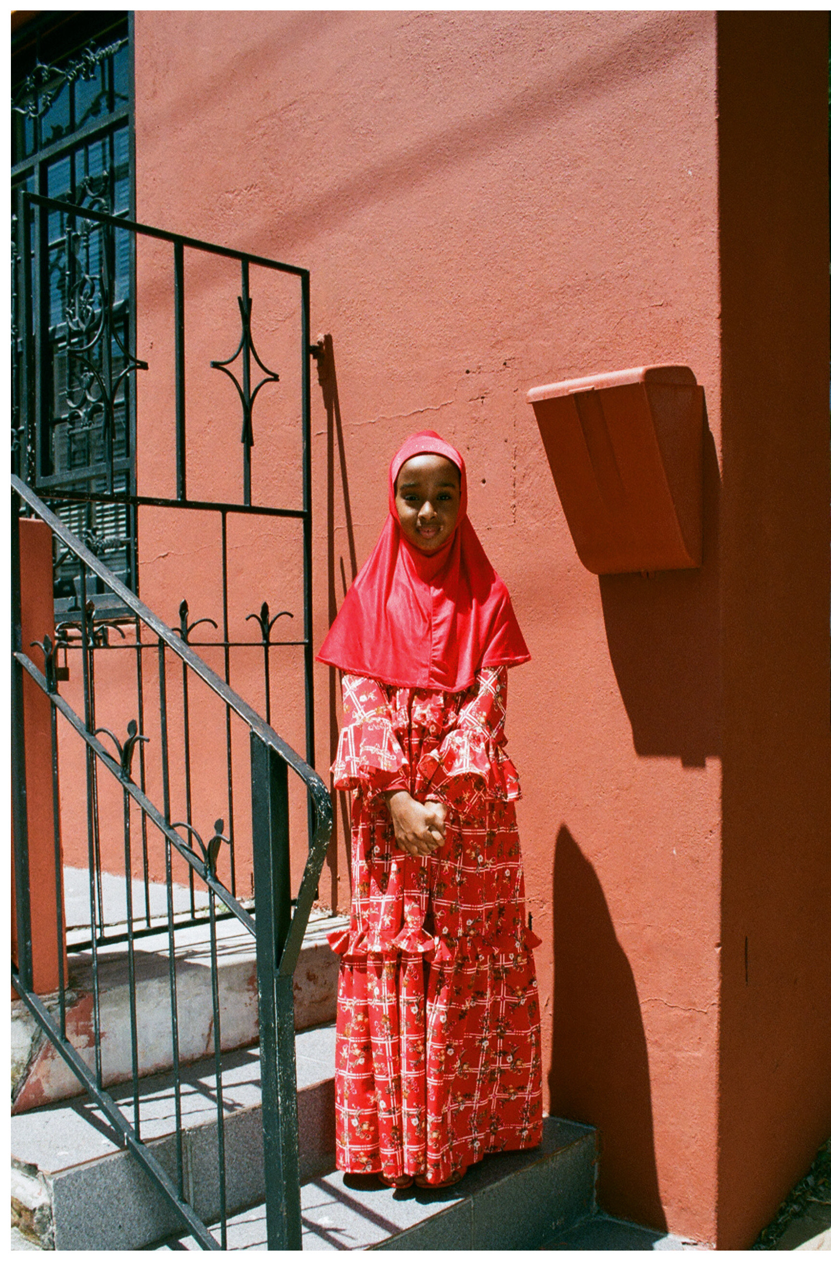 Heaven Lies At Thy Mothers Feet bu Faatimah Allie and Ya’eesh Dollie 5_Hijabi girl in red dress against orange wall