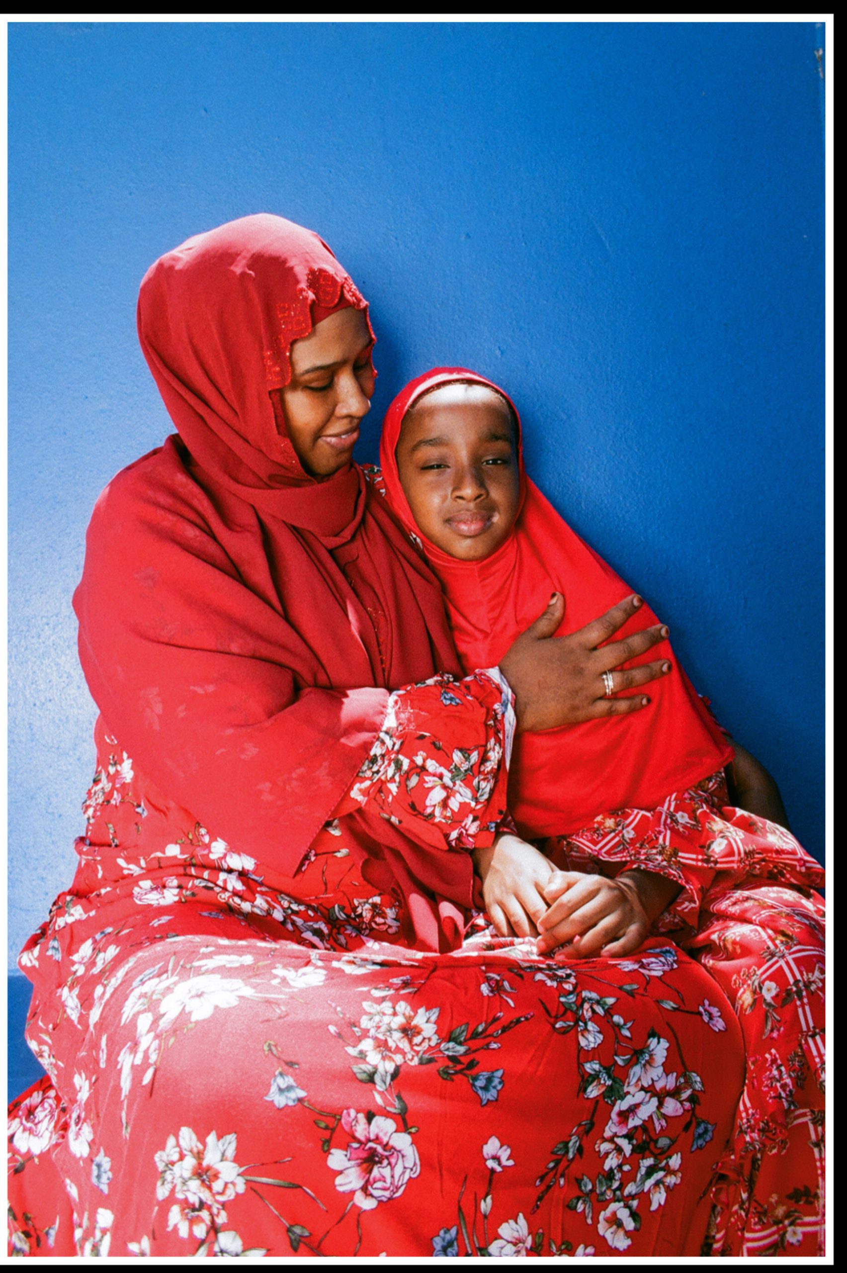 Heaven Lies At Thy Mothers Feet bu Faatimah Allie and Ya’eesh Dollie 9_Hijabi mother with holding daughter in floral red dress